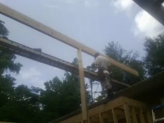 Carpenter setting a ridge beam over a new addition frame — Ice Dam Removal by Roofing Brothers in Coltons Point