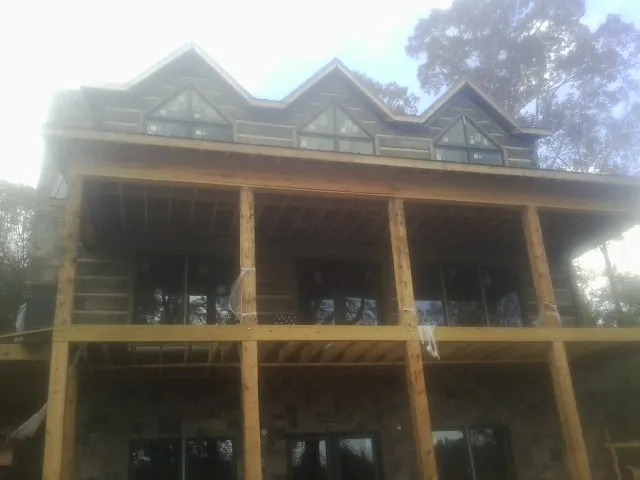 Dormers and porch framing on a large log home under construction — Roof Coating work by our crew in Coltons Point