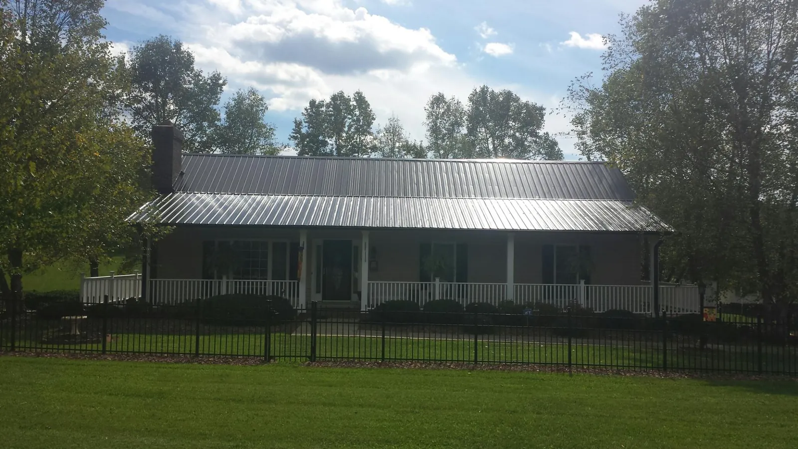 Gray metal roof on a brick ranch with a full width front porch — Gutter Guard Installation work by our crew in Coltons Point