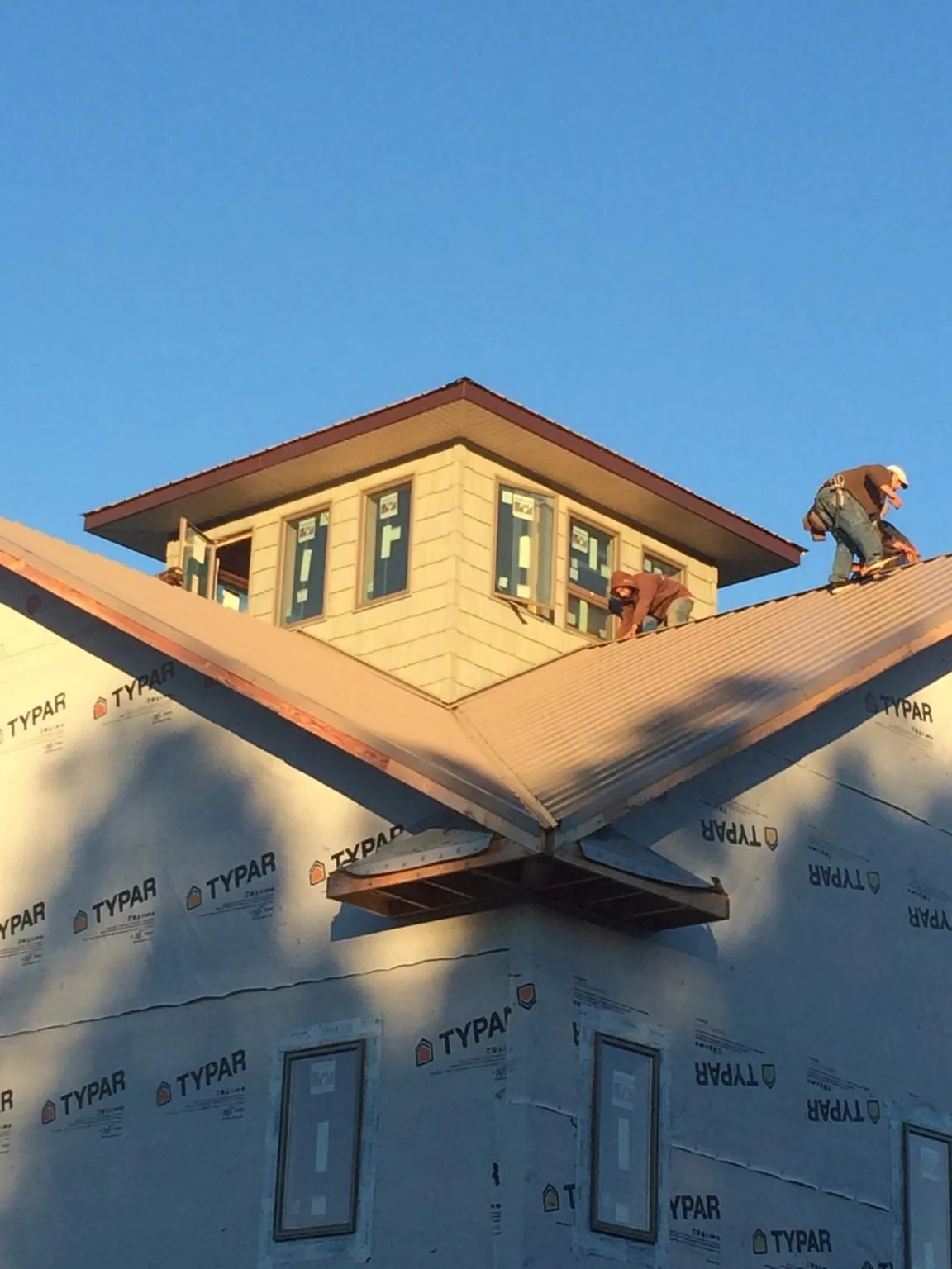 Roofers working around a rooftop cupola on a new metal roof at sunset — Roof Waterproofing in Coltons Point by Roofing Brothers